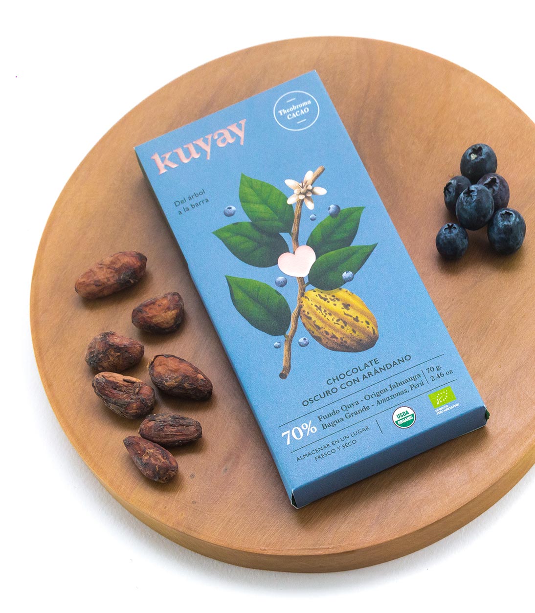 Kuyay arándano bar on a wooden board with cacao beans and blueberries