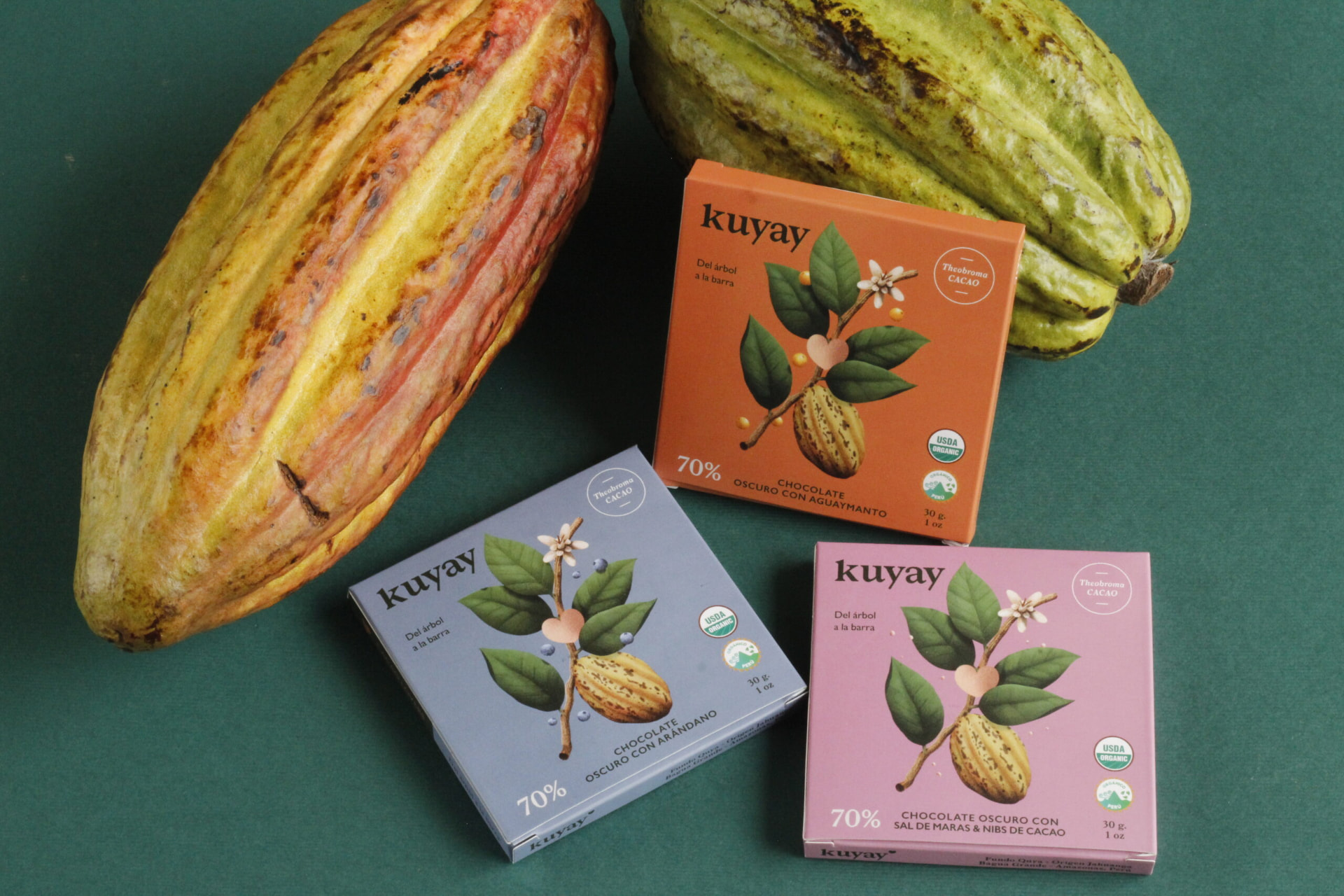 Three Kuyay 30 g bars on a green backdrop with cacao pods