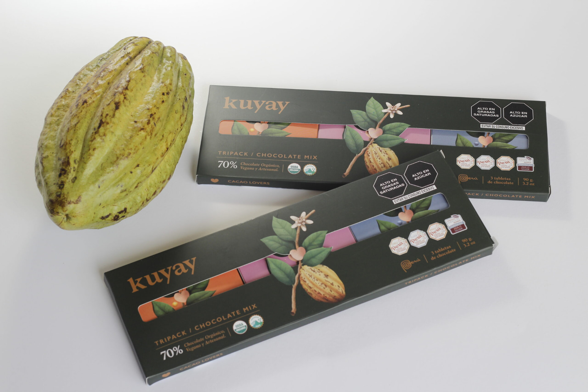 Two Kuyay tripack boxes beside a green cacao pod